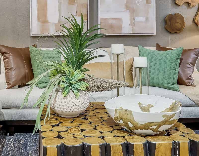 Stylish living room with beige sofa, green pillows, potted plant, and decorative coffee table centerpiece