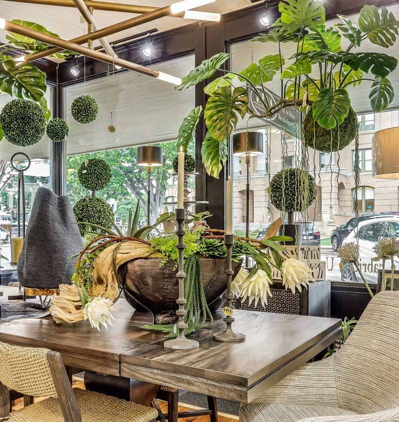 Stylish cafe interior with wooden table, woven chairs, hanging plants, and large windows