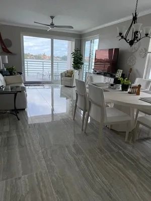 Bright open dining room with white furniture, glossy floor, chandelier, and sliding glass doors to a balcony.