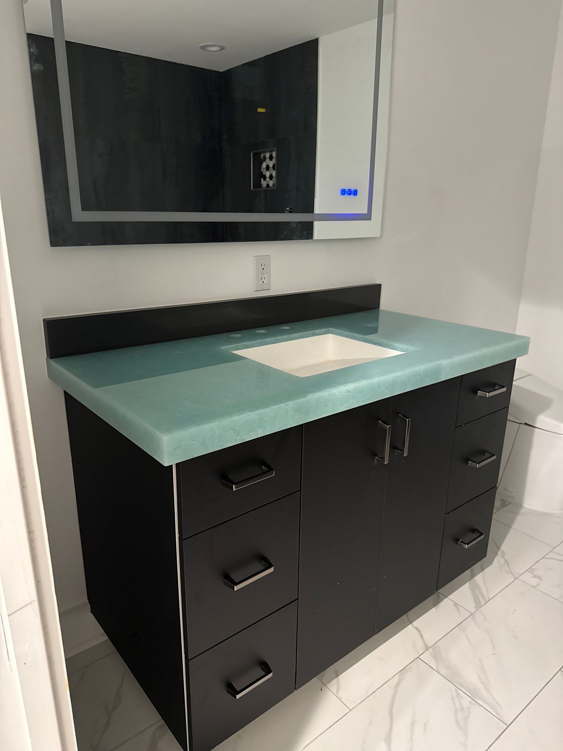 Modern bathroom vanity with countertop, sink, cabinets, and a large mirror with lights