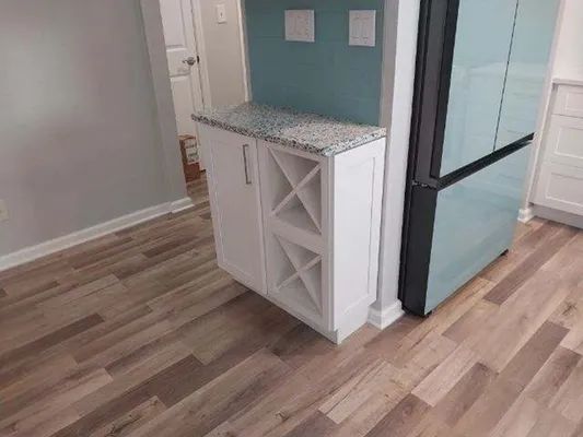 Small white cabinet with open shelves and a black-framed glass door on a light wood floor