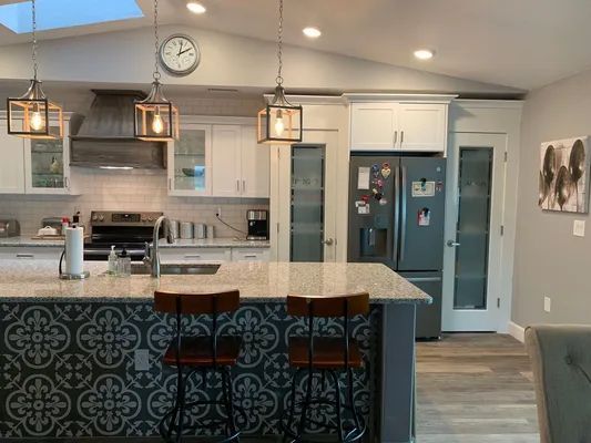 Modern kitchen with white cabinets, granite island, hanging pendant lights, and blue pantry doors