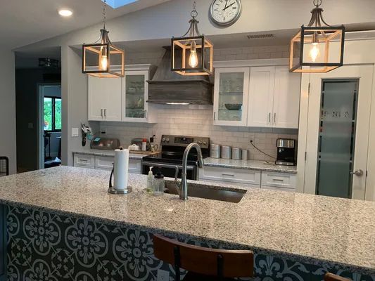 Modern kitchen with white cabinets, granite island, pendant lights, and stainless steel appliances