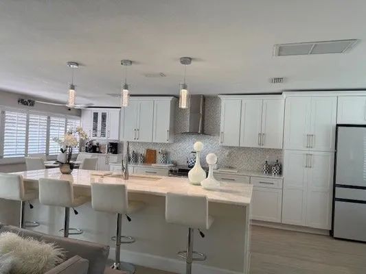 Bright modern kitchen with white cabinets, island seating, and stainless steel appliances