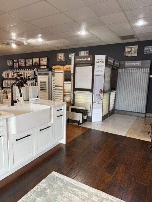 Showroom interior with display cabinets, flooring samples, and a dark wall with framed photos