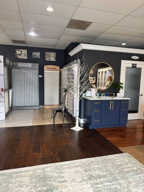 Interior of a lobby with dark wood floors, blue vanity, mirror, and a decorative white tree near a glass entry door