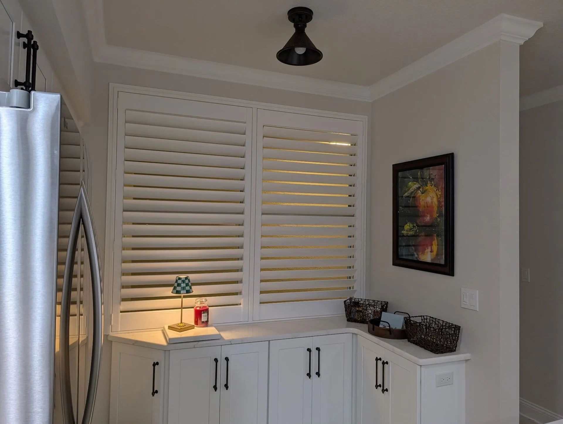 Laundry room with white cabinets, shuttered window, stainless refrigerator, and small countertop decor