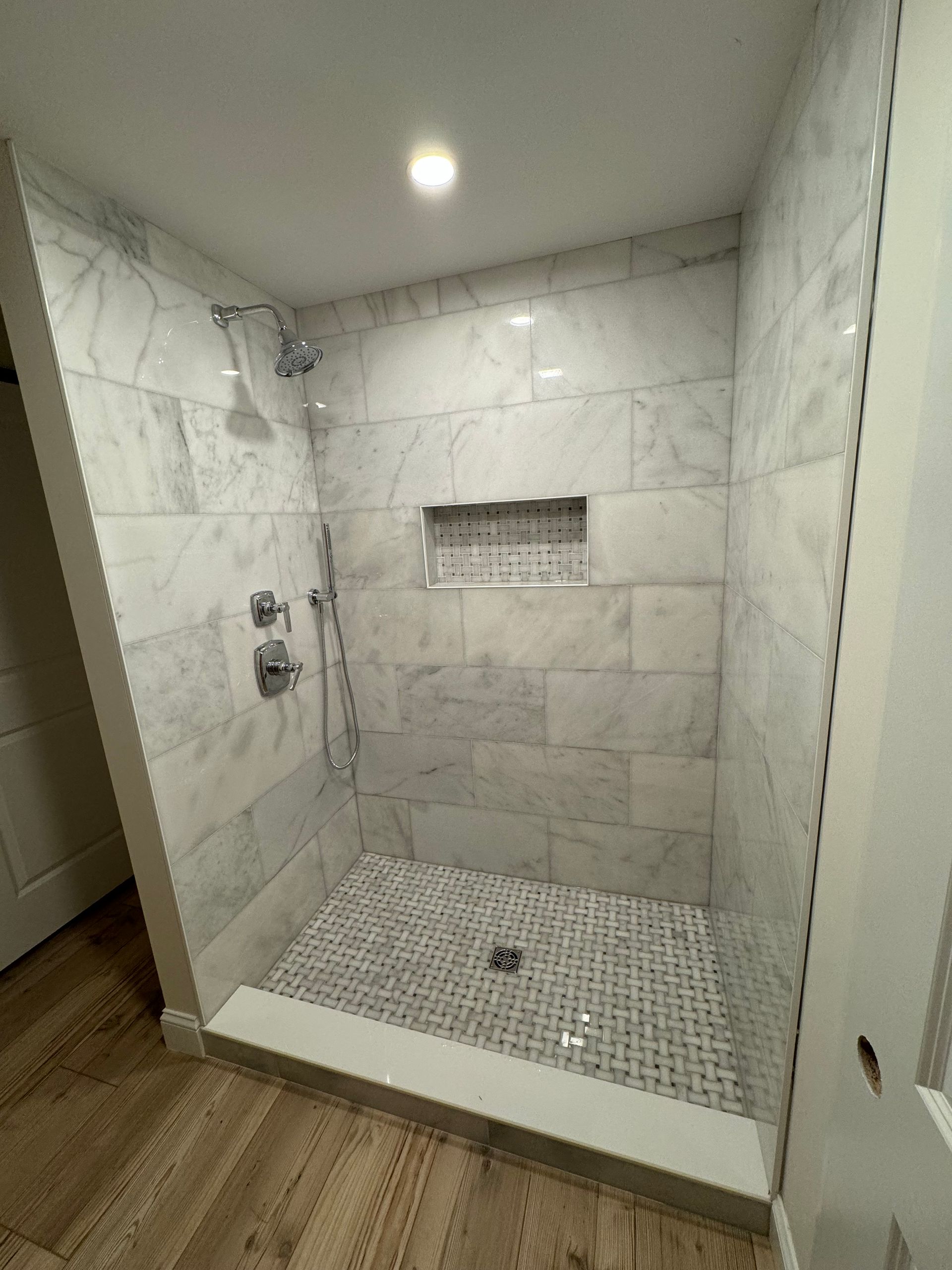A bathroom with a walk in shower and marble tiles.