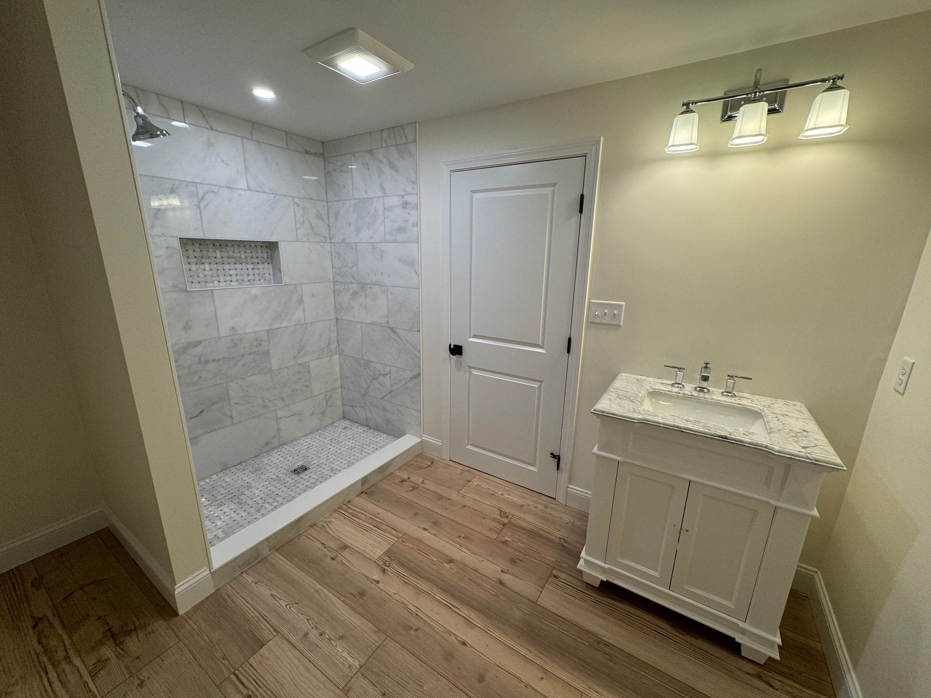 A bathroom with a walk in shower and a sink.