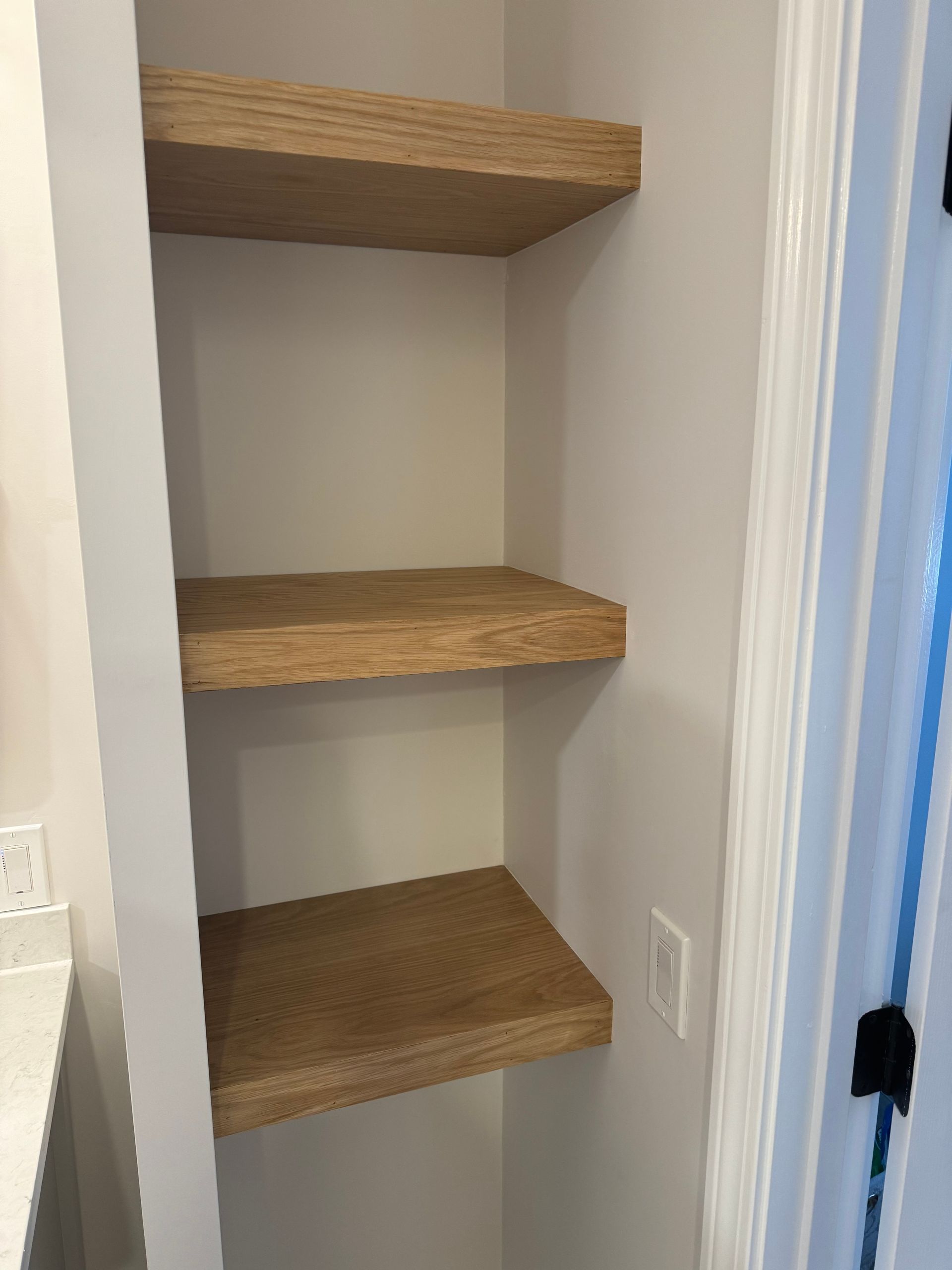 There are three shelves in the corner of a room.