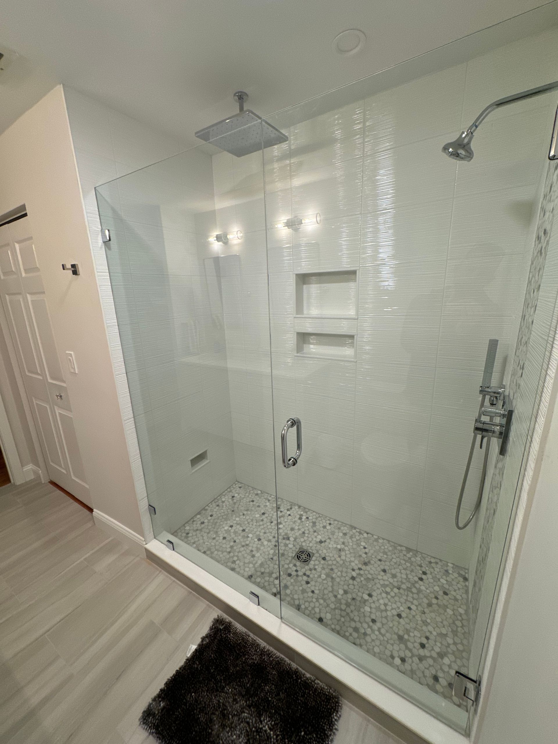 A bathroom with a walk in shower with a glass door.