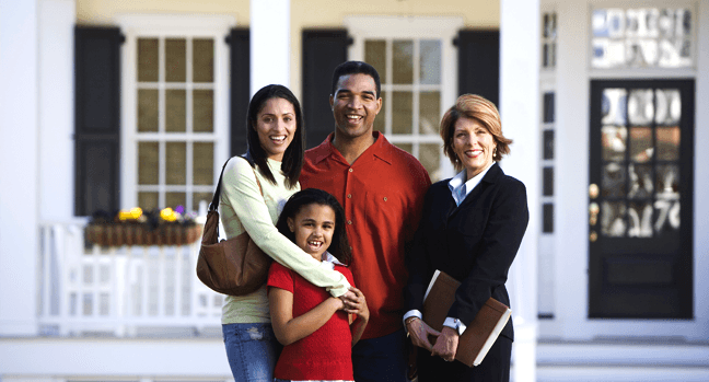Real estate agent with happy family in front of a home