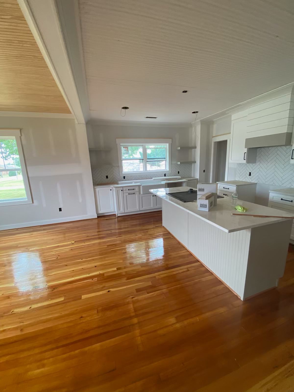 A kitchen in a house features hardwood floors and white cabinets