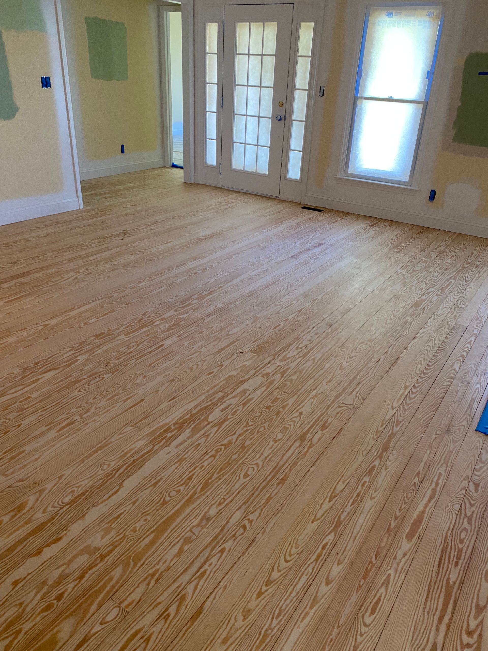 A living room with a wooden floor and sliding glass doors.