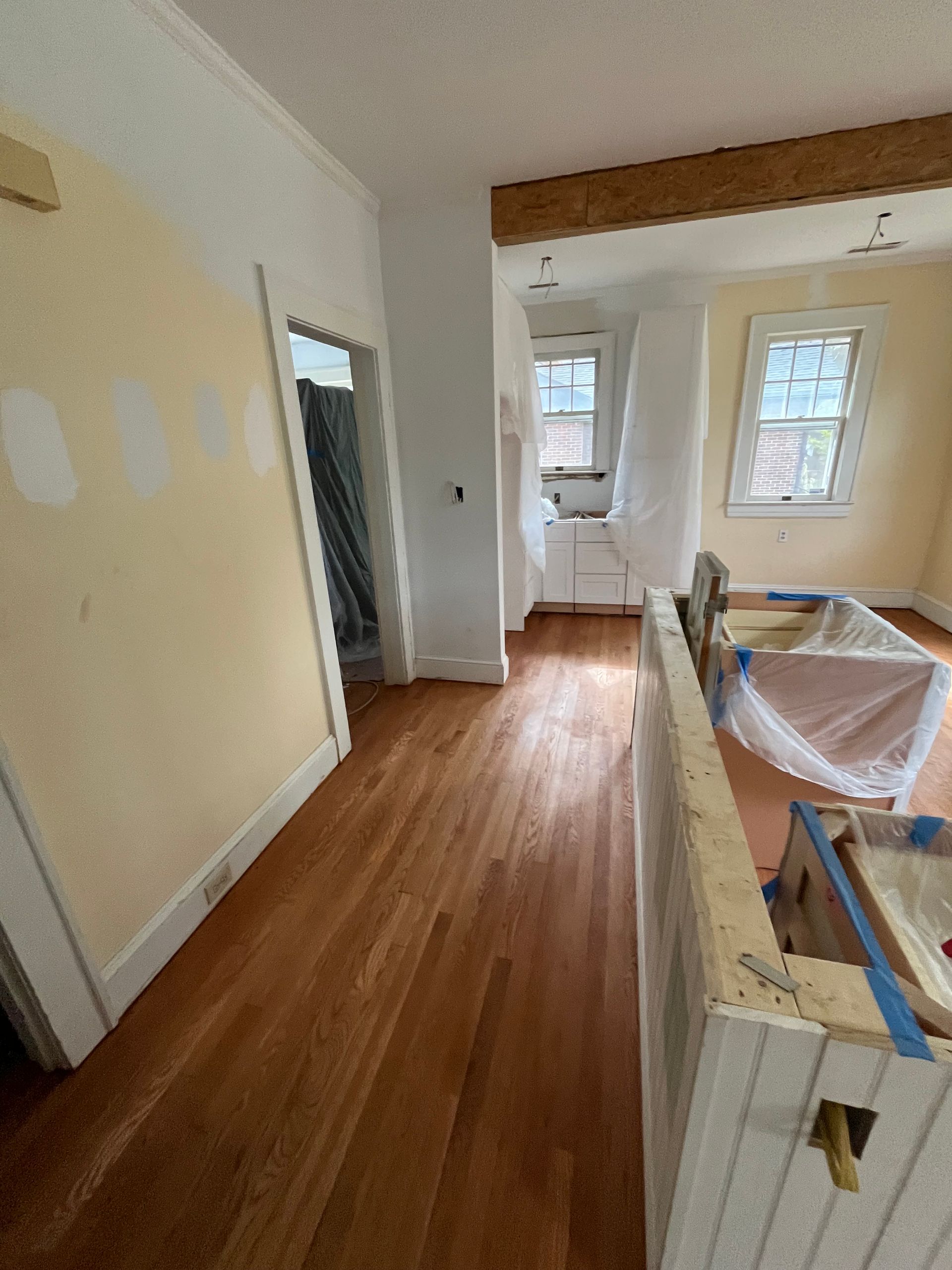 A room with hardwood floors and white walls is being painted.
