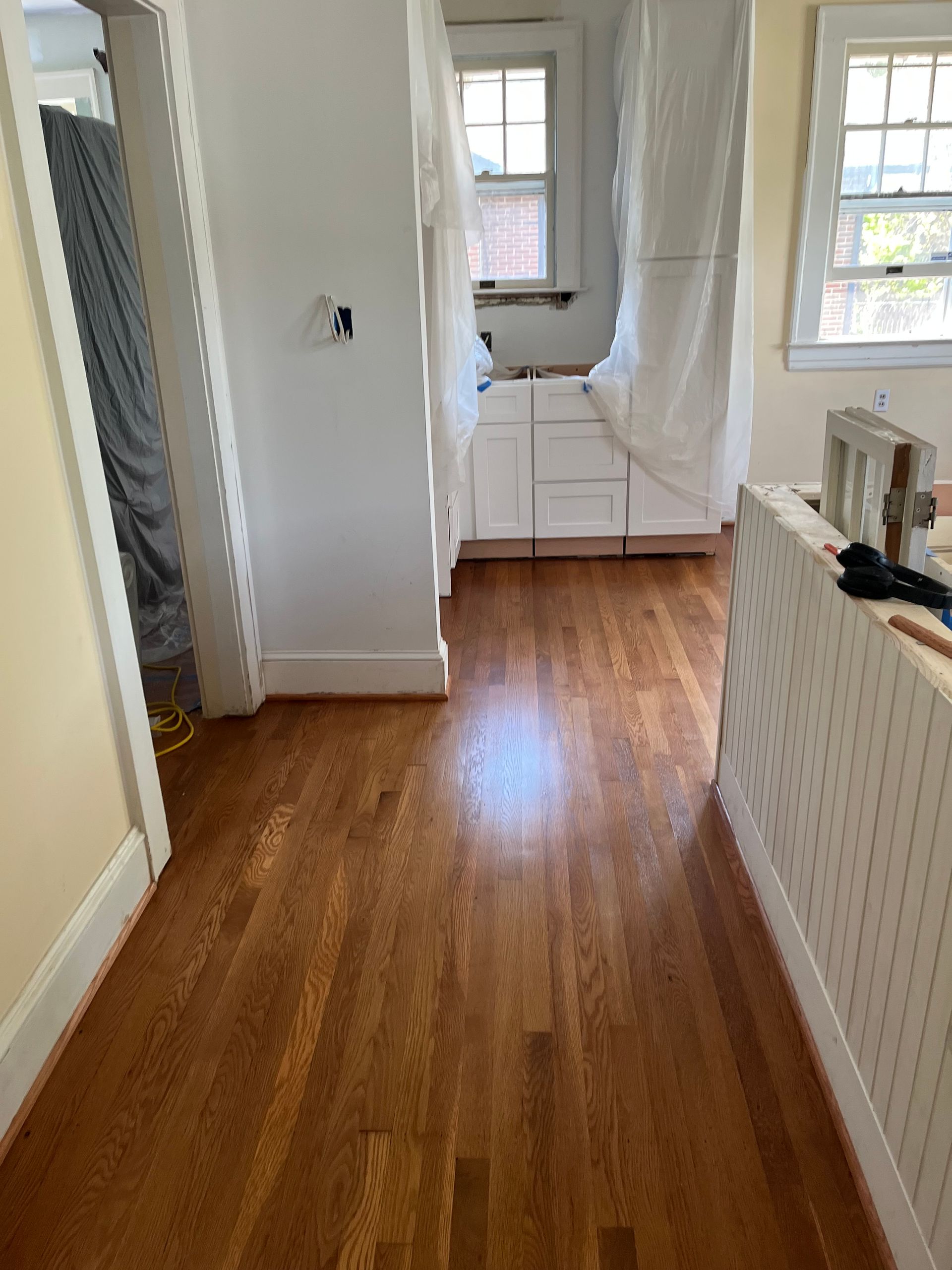 A hallway in a house with hardwood floors and white cabinets.