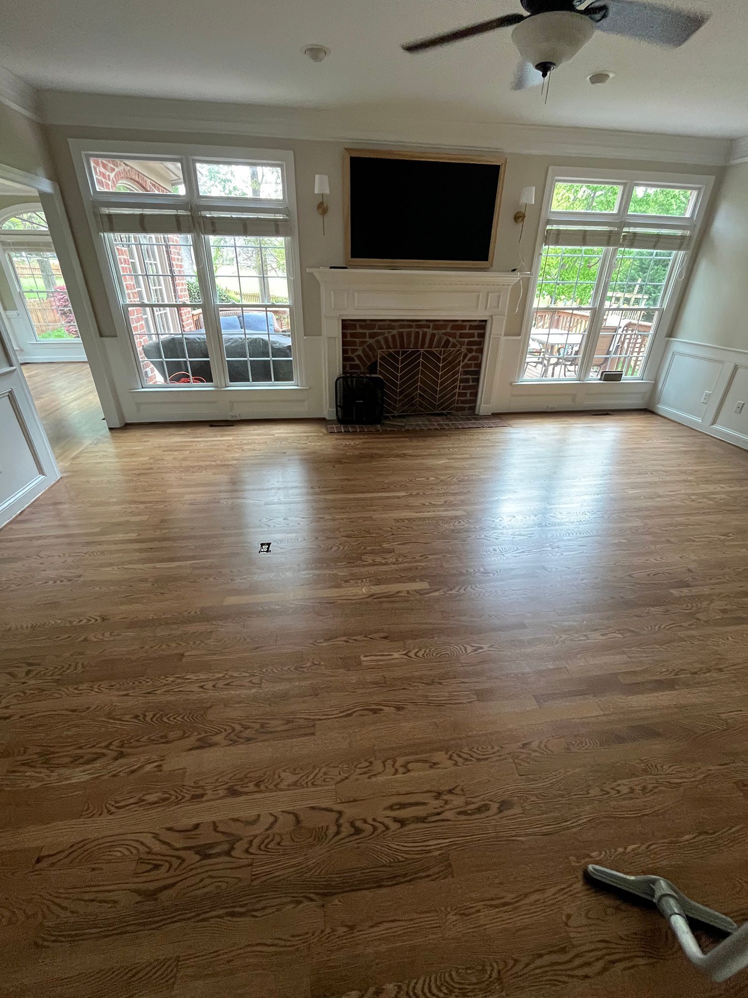 A living room with hardwood floors, a fireplace, and a flat-screen TV.