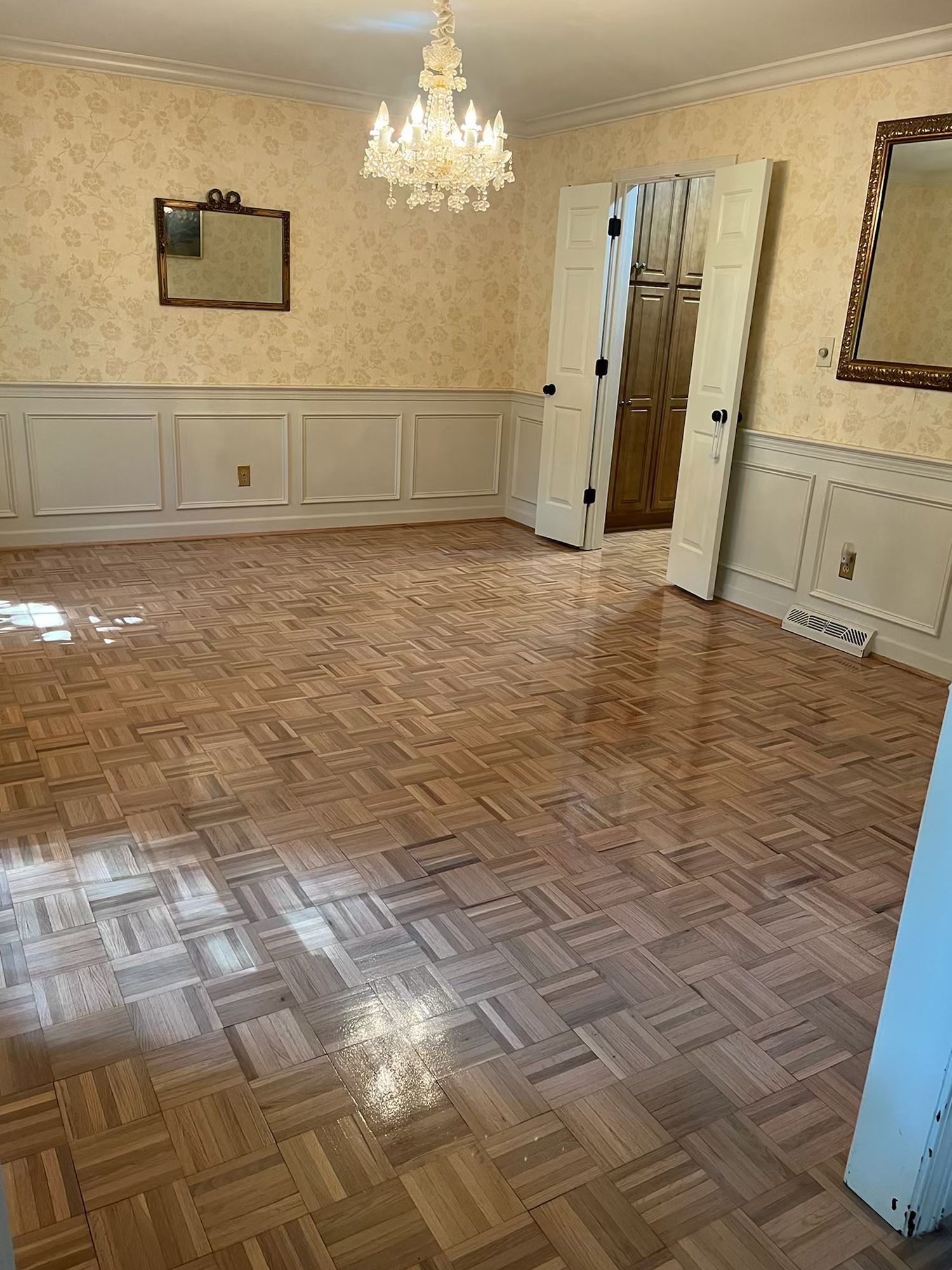 An empty room with a wooden floor and a chandelier.
