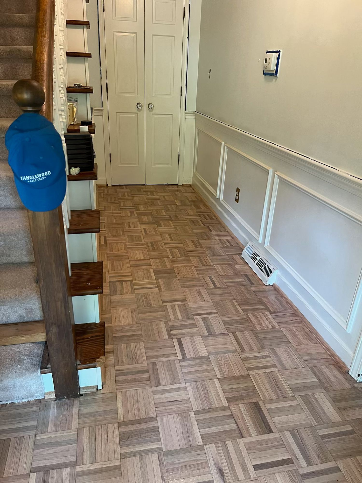 A hallway with a wooden floor and stairs in a house.