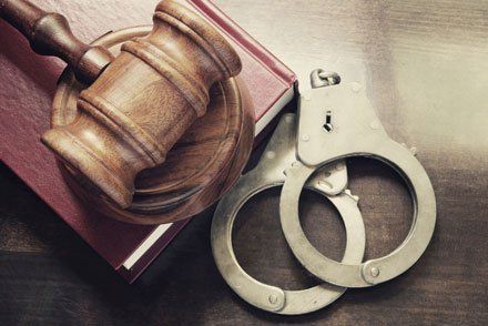 Gavel and handcuffs with red legal book on wooden table