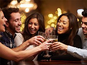 A group of people are toasting with wine glasses at a bar.