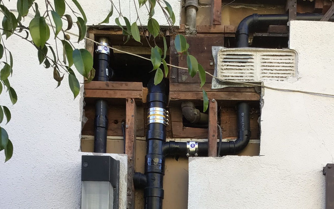Plumber using a wrench under a sink. Various tools and supplies are nearby.