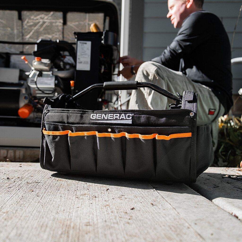 A man is sitting next to a tool bag that says general on it.