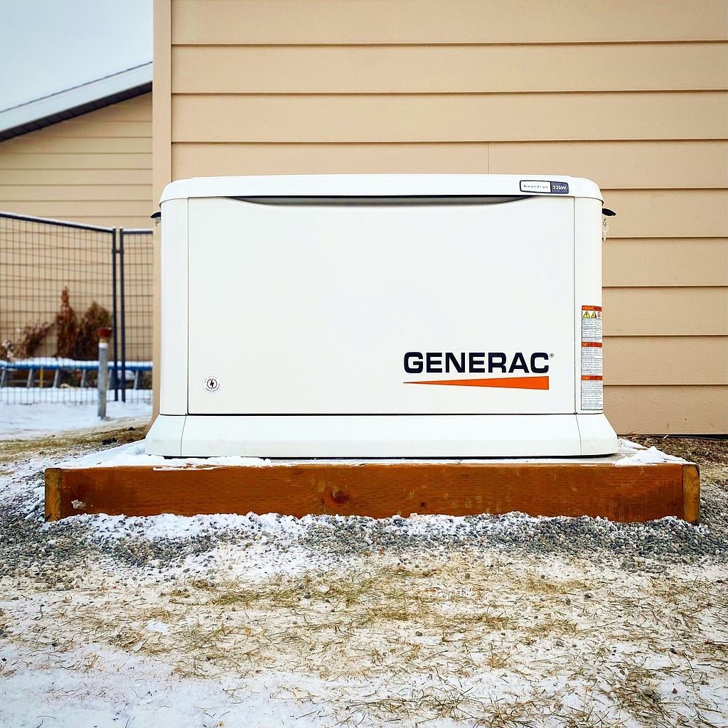 A generator is sitting outside of a house in the snow.
