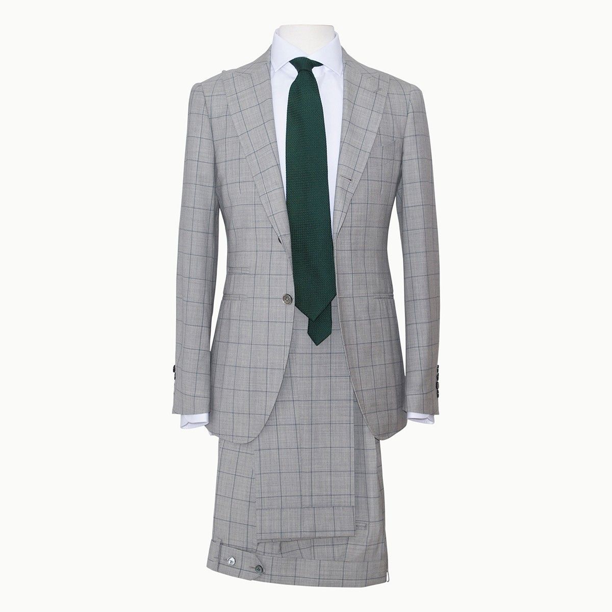 A gray suit with a subtle block pattern, worn with a white dress shirt and a dark green necktie, displayed on a mannequin.