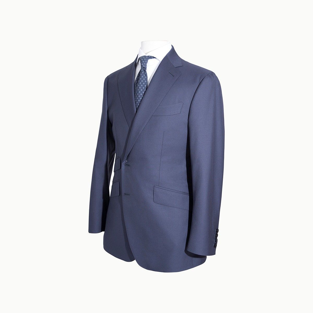 A dark blue suit jacket worn over a light dress shirt and patterned blue tie on a mannequin.