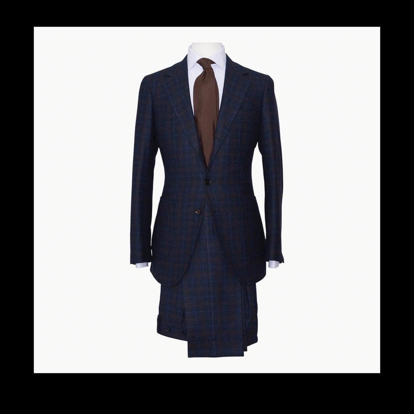 A dark blue plaid suit jacket worn over a light shirt with a brown necktie on a mannequin.