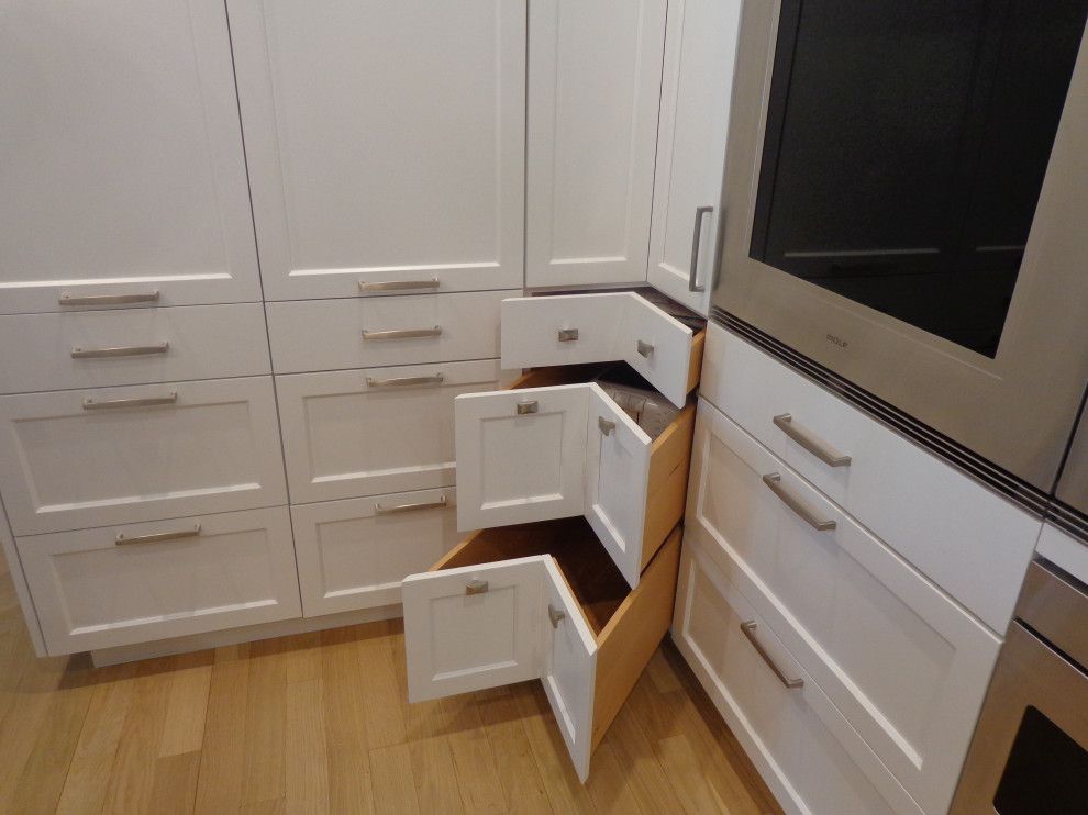A kitchen with white cabinets and wooden drawers.