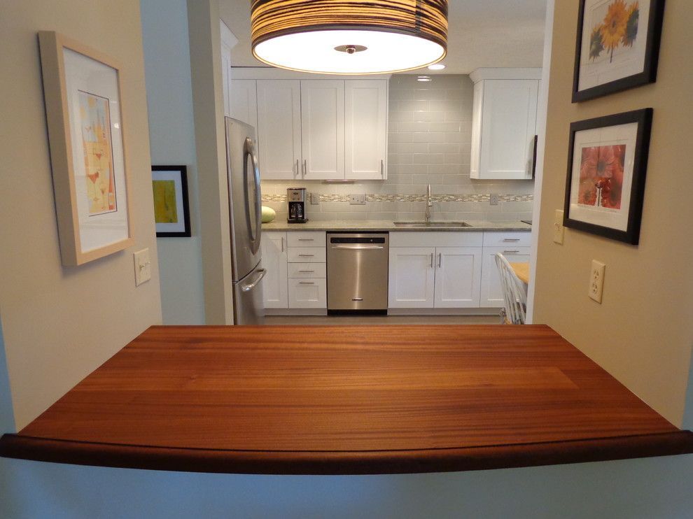 A kitchen with white cabinets and a wooden counter top.