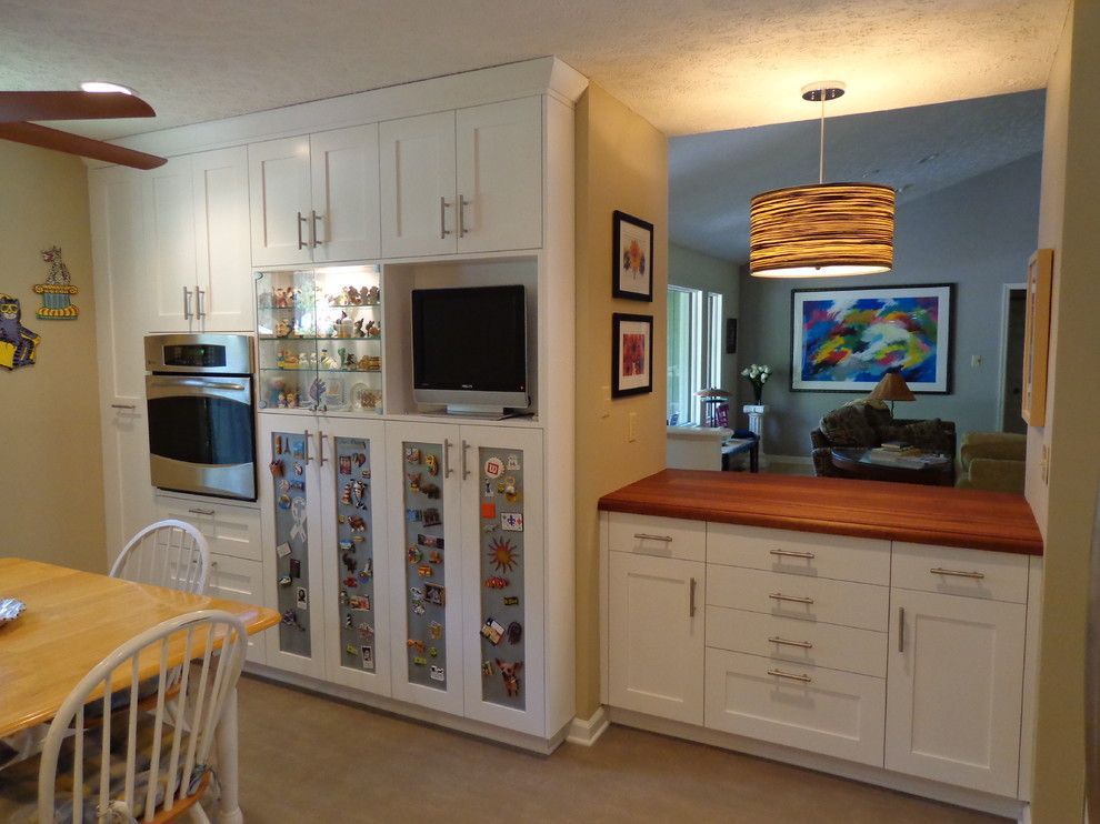 A kitchen with white cabinets, a table and chairs and a television.