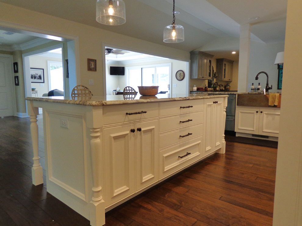 A kitchen with white cabinets and a large island in the middle.