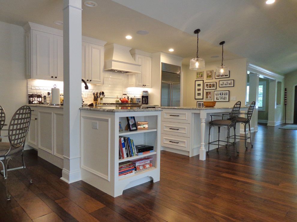 A kitchen with white cabinets and hardwood floors.