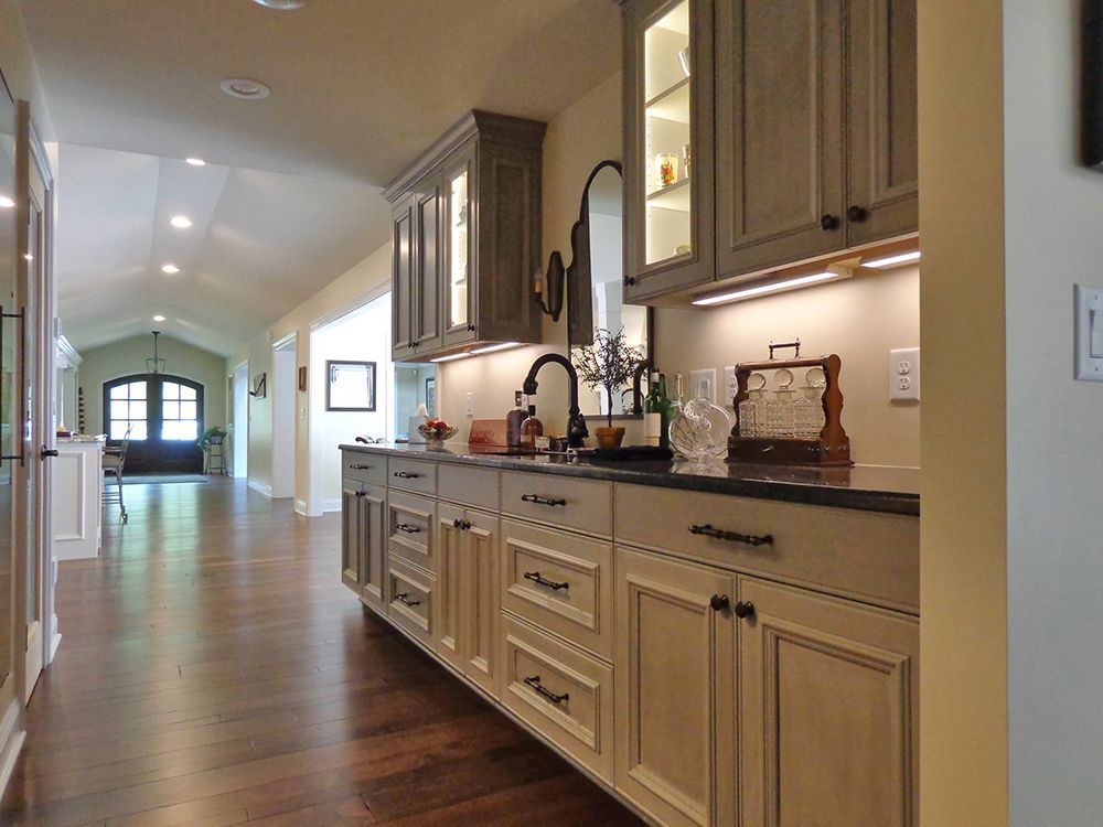 A kitchen with a sink , cabinets and a mirror.