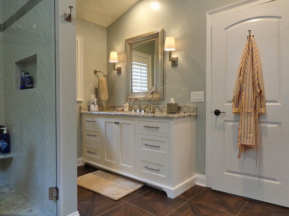 A bathroom with two sinks, a mirror, and a walk in shower.