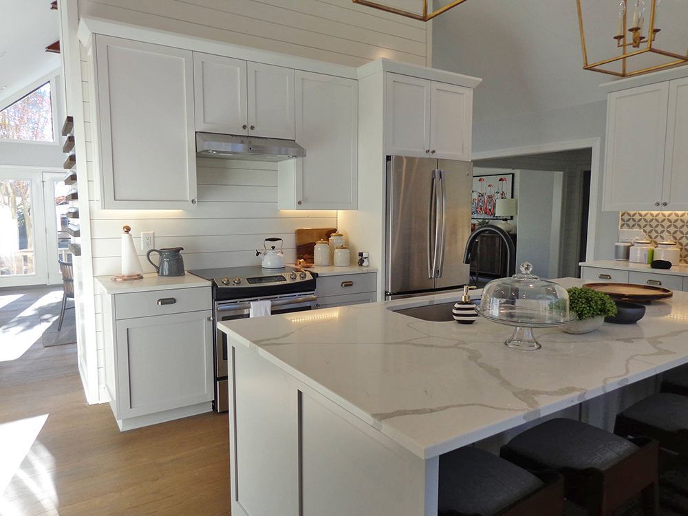 A kitchen with white cabinets, stainless steel appliances, and a large island.