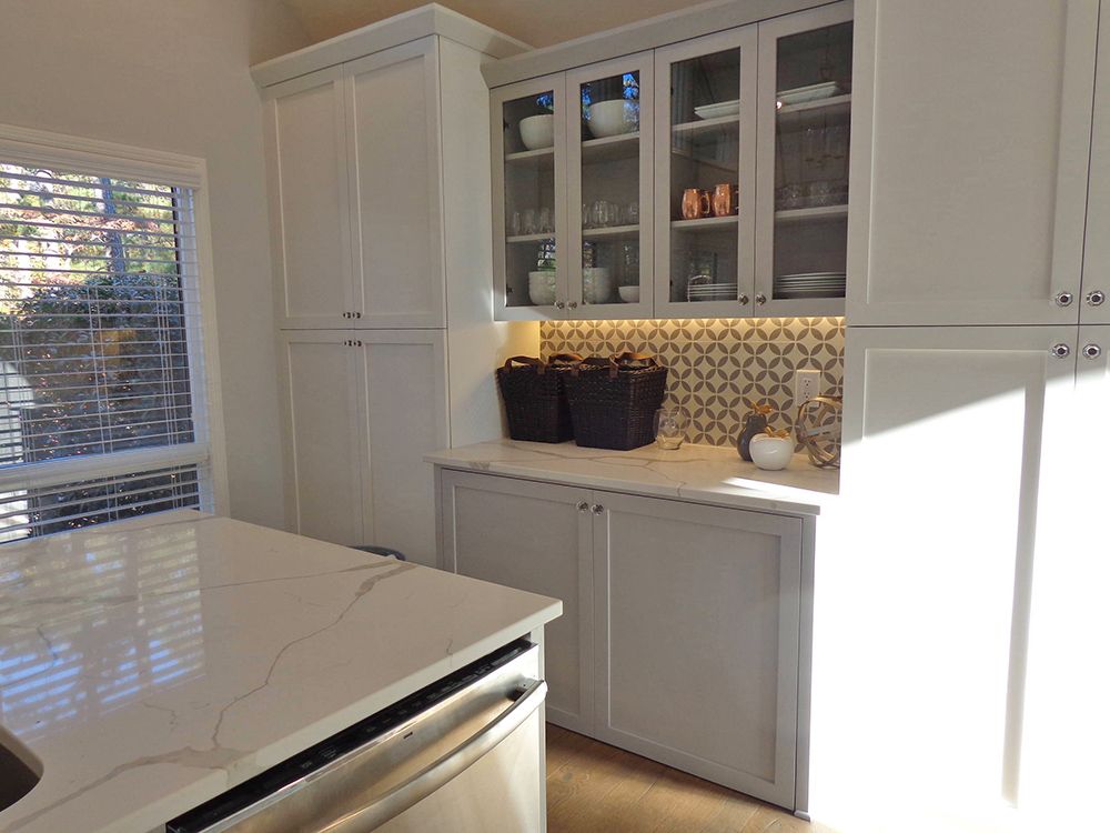 A kitchen with white cabinets, a sink, and a window.