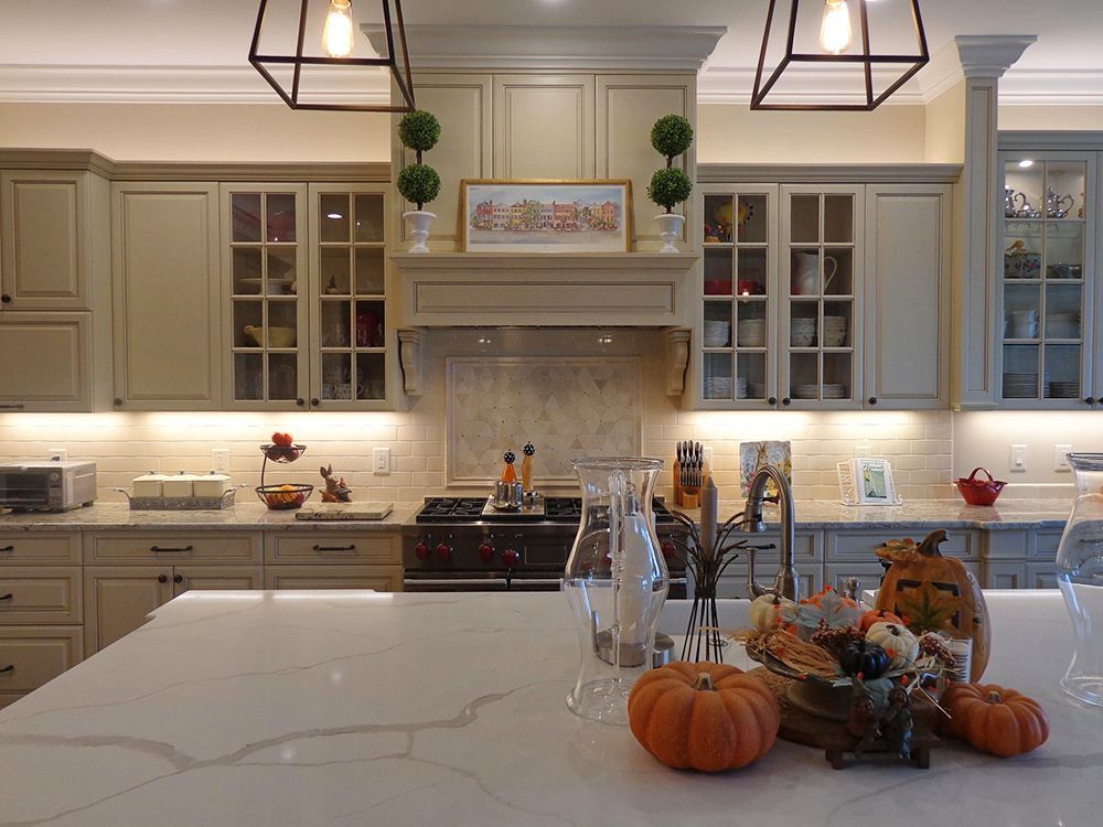 A kitchen with white cabinets and pumpkins on the counter.