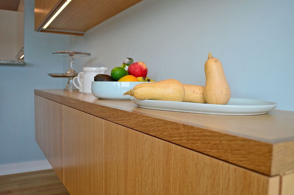A wooden counter top with a bowl of fruit and vegetables on it.