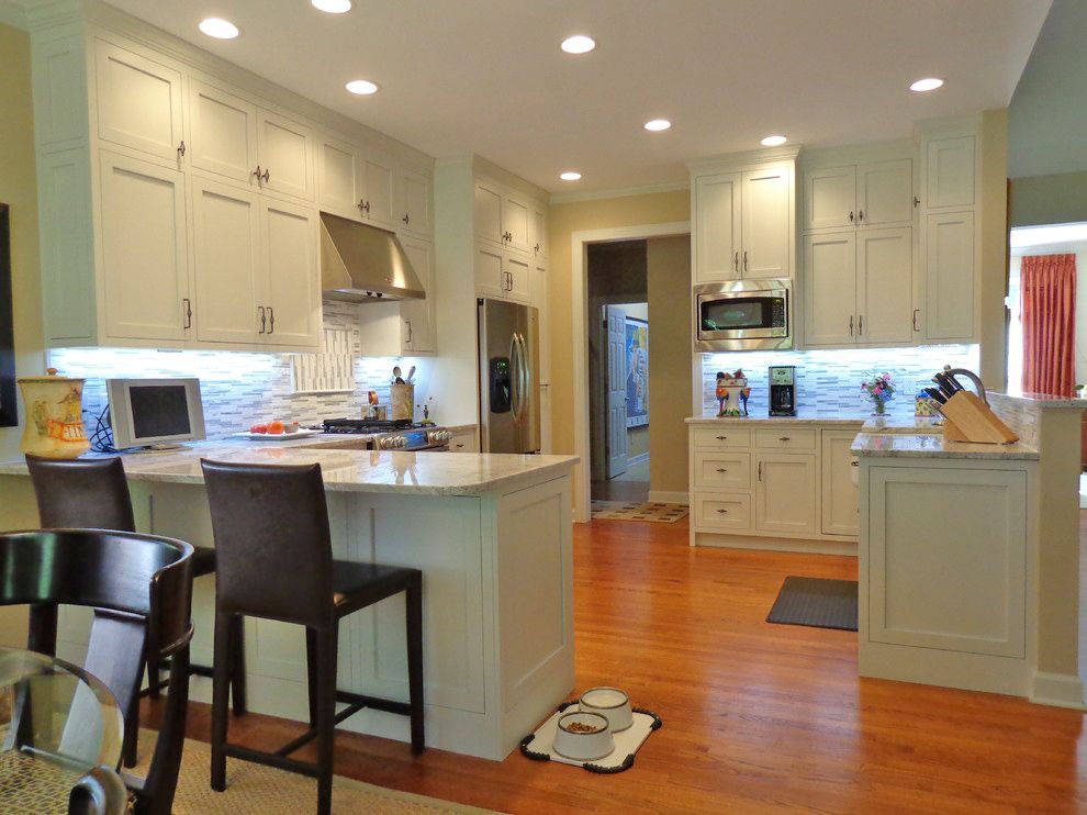 A kitchen with white cabinets, stainless steel appliances and hardwood floors.
