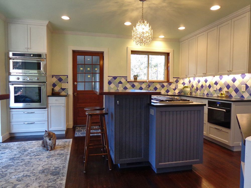 A kitchen with white cabinets and a blue island.