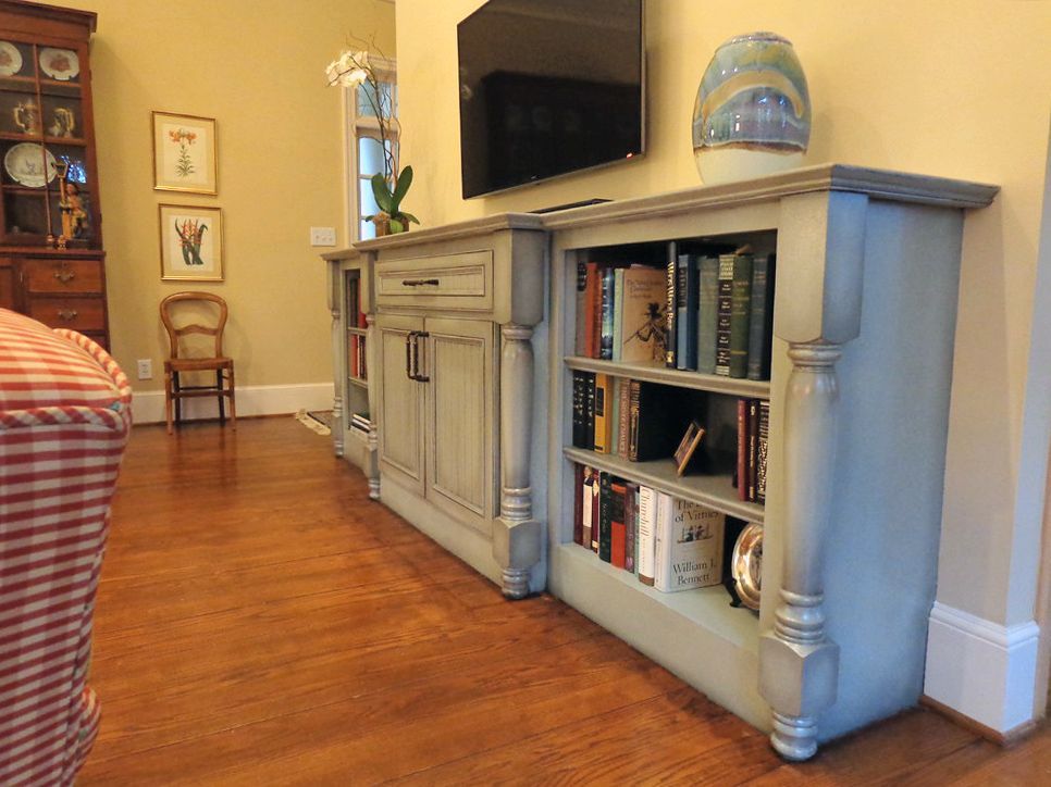 A living room with a bookshelf and a television on the wall.