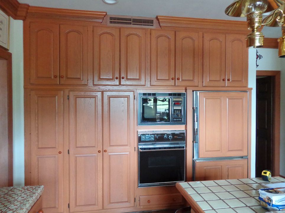 A kitchen with lots of wooden cabinets and appliances.