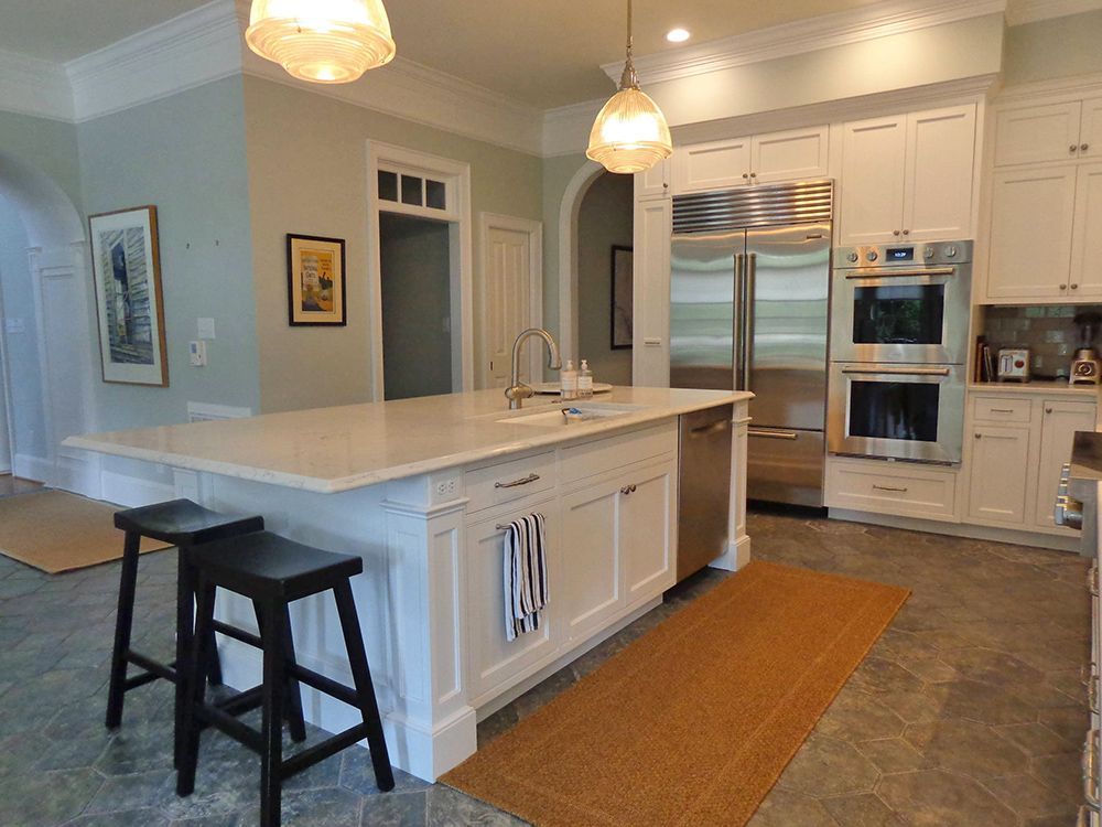A kitchen with white cabinets, stainless steel appliances and a large island.