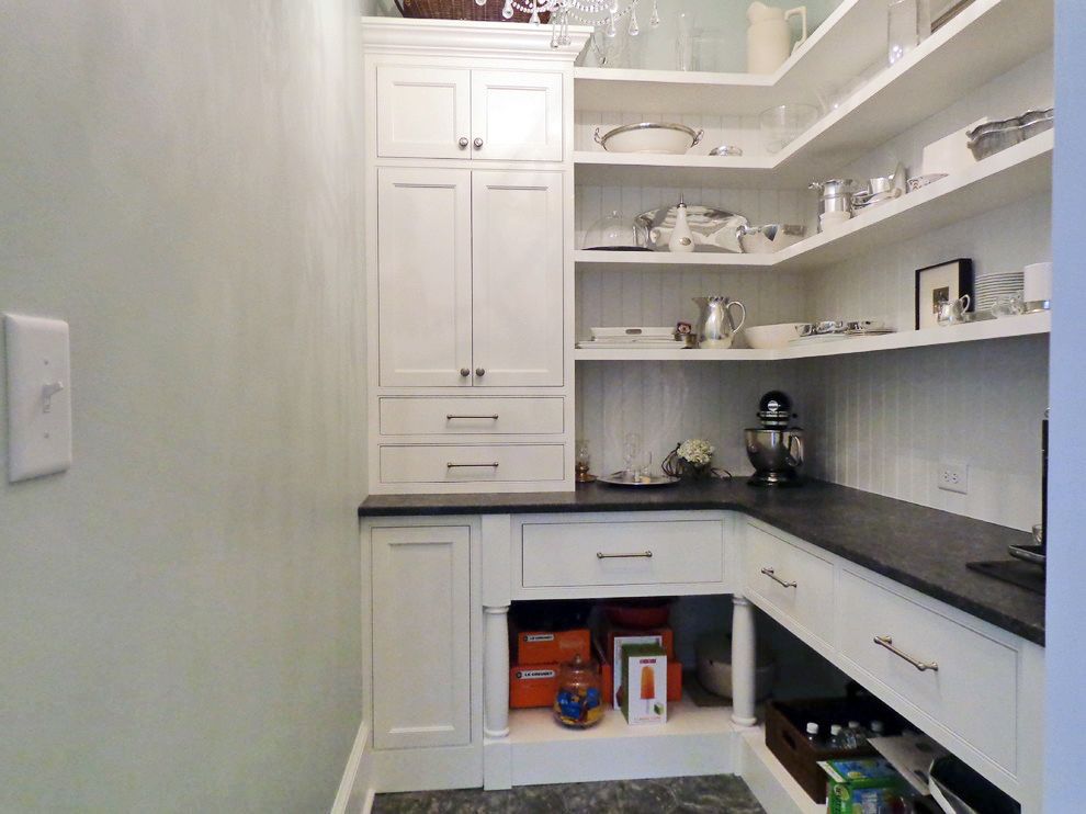 A kitchen pantry with white cabinets and black counter tops.