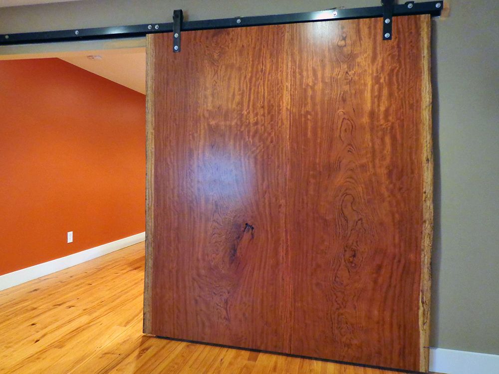 A wooden sliding barn door is open in a room with hardwood floors.