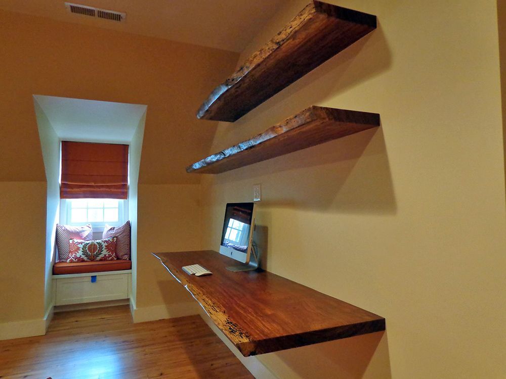 A room with three wooden shelves and a window seat.